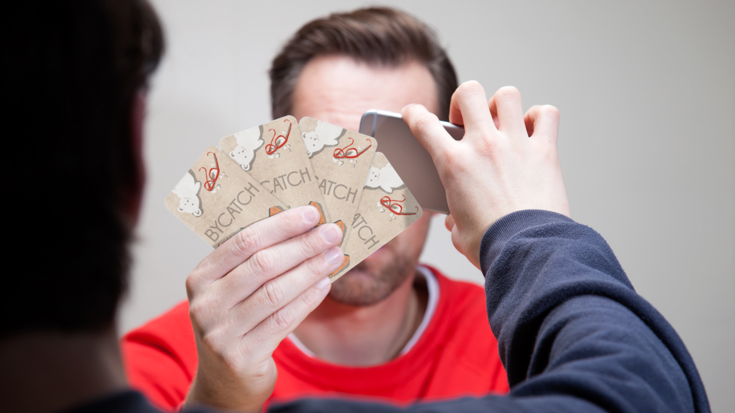 A Bycatch player surveilling an opponent's hand of cards